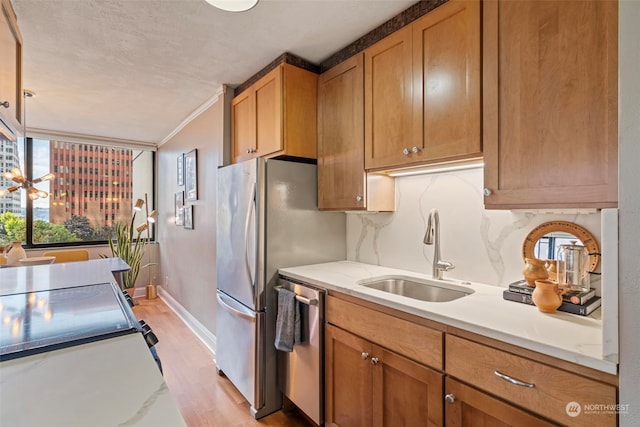 kitchen featuring crown molding, tasteful backsplash, sink, stainless steel dishwasher, and light hardwood / wood-style floors