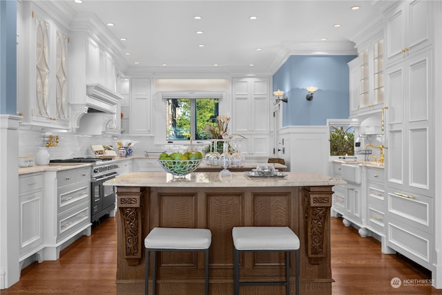 kitchen with range with two ovens, a kitchen island, dark hardwood / wood-style flooring, and white cabinetry