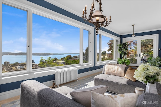 sunroom / solarium with a water view, an inviting chandelier, and radiator heating unit