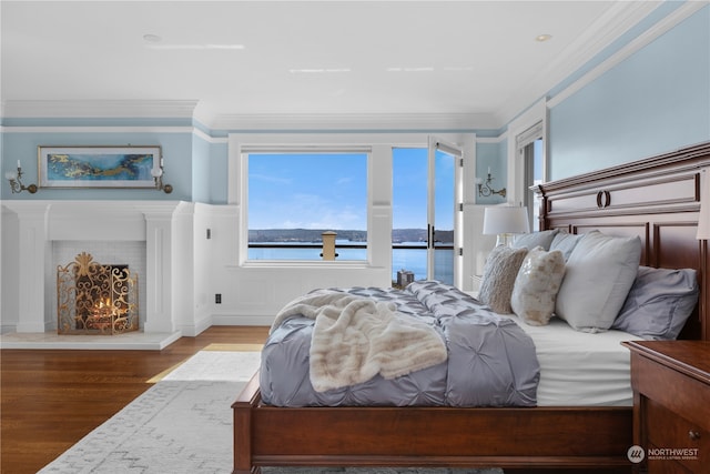 bedroom with crown molding, a water view, and hardwood / wood-style floors