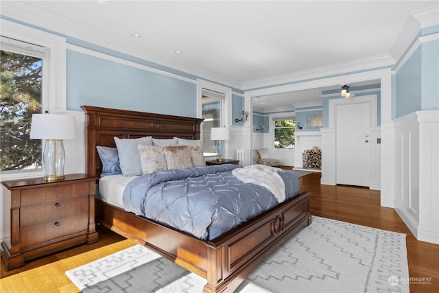 bedroom featuring ornamental molding, light wood-type flooring, multiple windows, and radiator