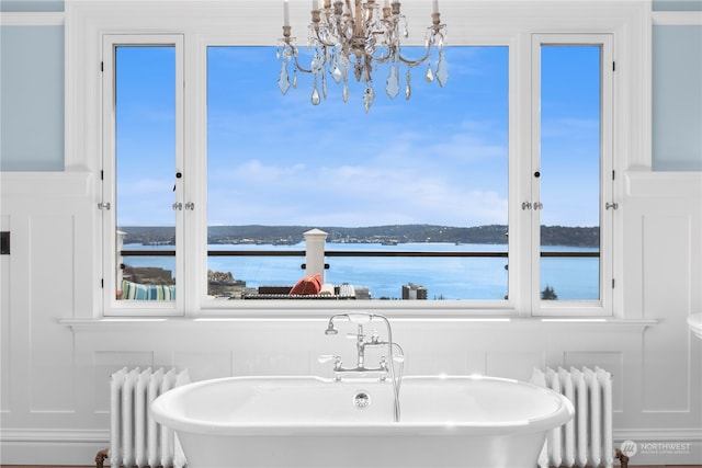 bathroom featuring a water view, a washtub, radiator heating unit, and a notable chandelier