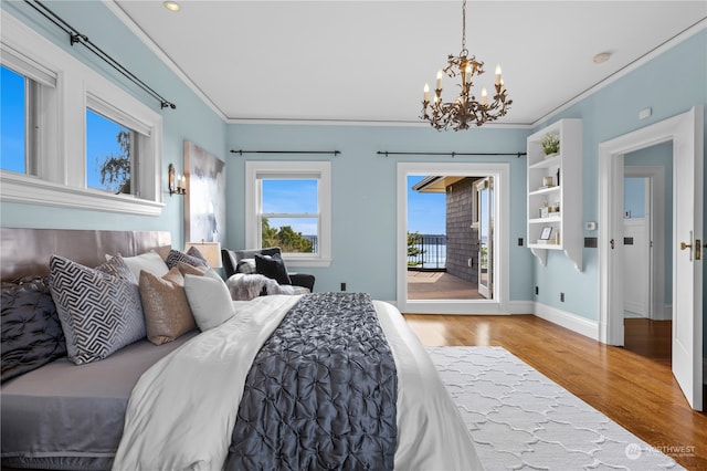 bedroom with light wood-type flooring, crown molding, a chandelier, and access to exterior