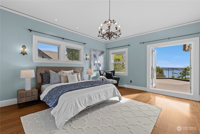 bedroom with access to outside, hardwood / wood-style flooring, crown molding, and a chandelier