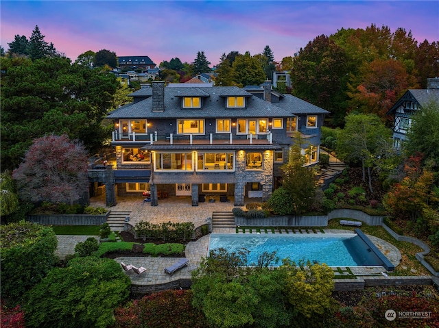 back house at dusk with a patio and a balcony