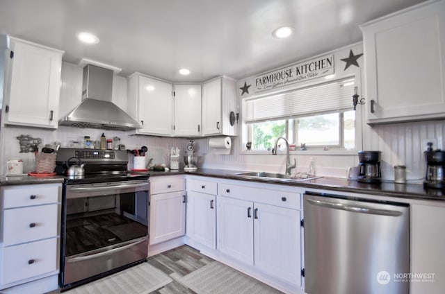 kitchen with stainless steel appliances, sink, wall chimney range hood, and white cabinets