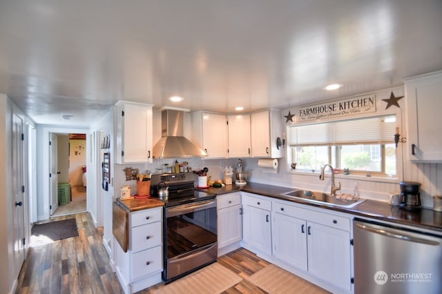 kitchen featuring white cabinetry, sink, wall chimney exhaust hood, appliances with stainless steel finishes, and light hardwood / wood-style floors