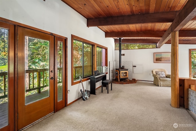 sunroom / solarium featuring a healthy amount of sunlight, beam ceiling, and a wood stove