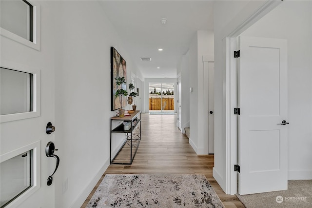 hallway featuring light wood finished floors, recessed lighting, visible vents, and baseboards