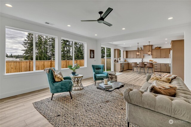 living room with ornamental molding, ceiling fan, and light hardwood / wood-style floors