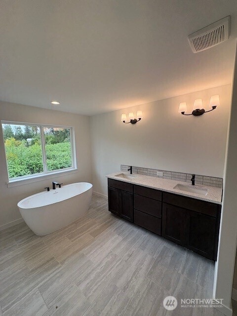 16220 76th Avenue Ct E, Puyallup, WA 98375 - bathroom featuring a freestanding bath, wood finished floors, baseboards, and vanity