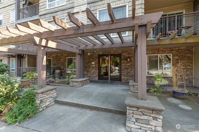 property entrance with a balcony, a pergola, and a patio