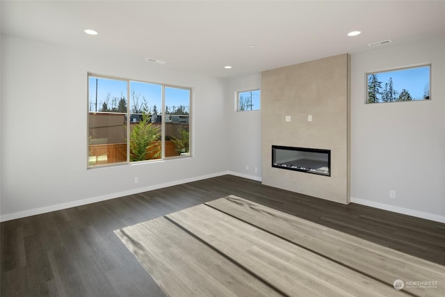 unfurnished living room with baseboards, a fireplace, visible vents, and wood finished floors