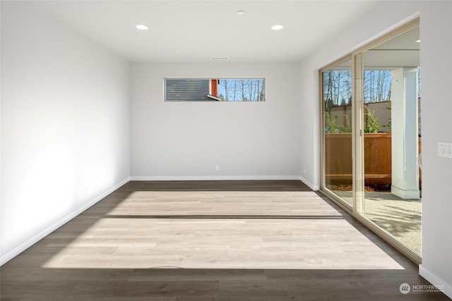 empty room with plenty of natural light, baseboards, wood finished floors, and recessed lighting