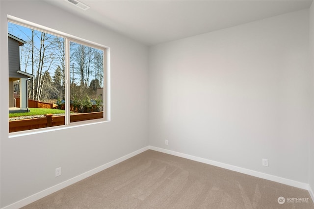 spare room with carpet, visible vents, and baseboards