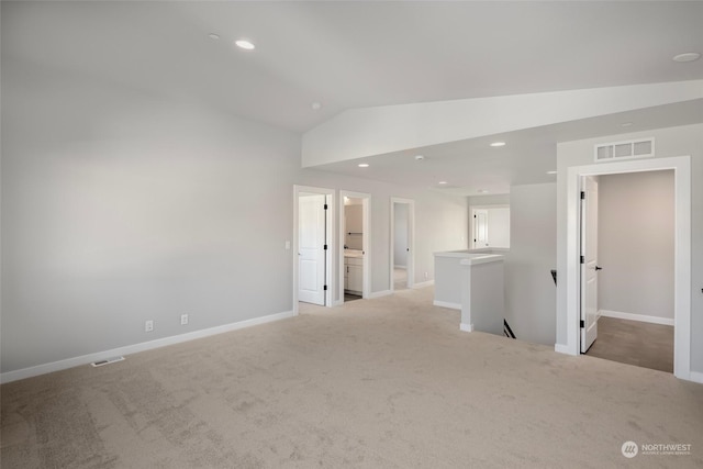 spare room with vaulted ceiling, light carpet, visible vents, and recessed lighting