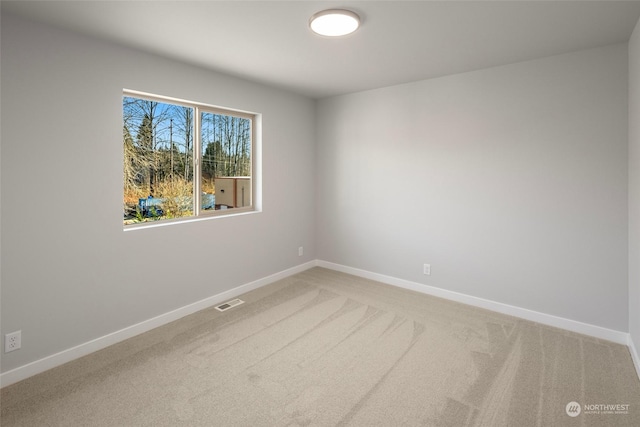 empty room with light carpet, visible vents, and baseboards