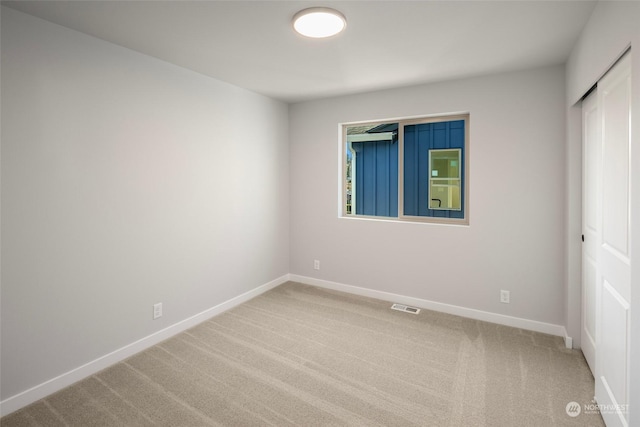 carpeted spare room featuring visible vents and baseboards