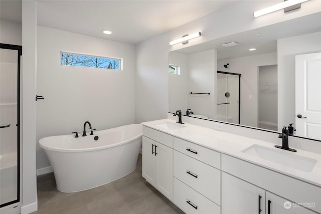 bathroom featuring double vanity, a soaking tub, a shower stall, and a sink