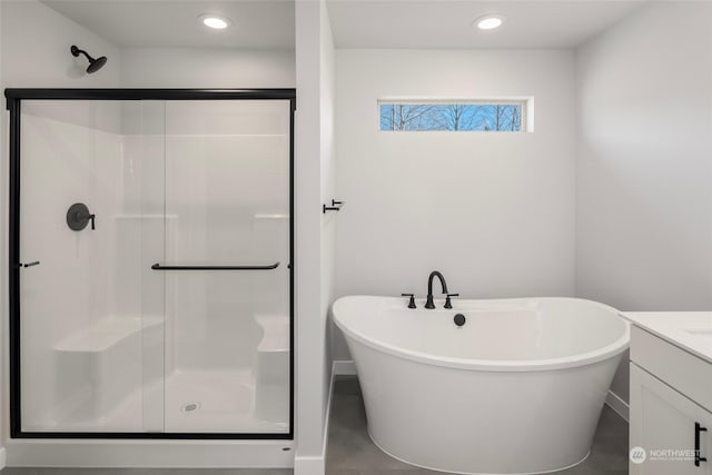 bathroom featuring a stall shower, a freestanding tub, and vanity