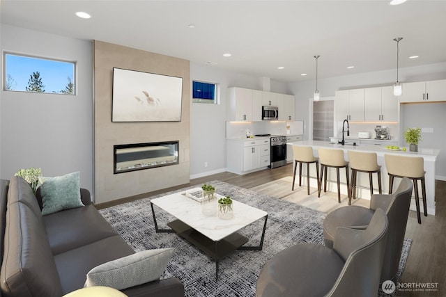 living room with light wood finished floors, recessed lighting, a fireplace, and baseboards