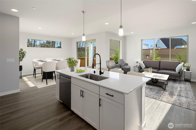 kitchen with dark wood-style floors, dishwasher, light countertops, and a sink