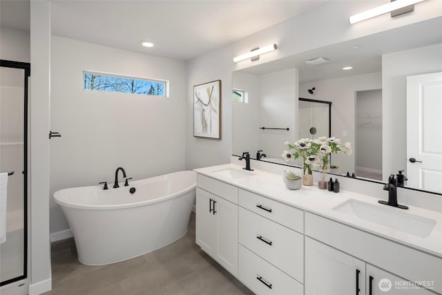 full bath featuring a sink, a freestanding tub, a stall shower, and double vanity