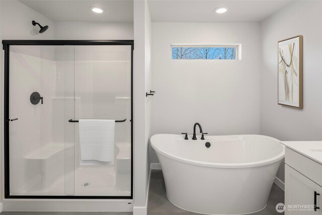 bathroom featuring recessed lighting, a shower stall, a freestanding bath, and vanity