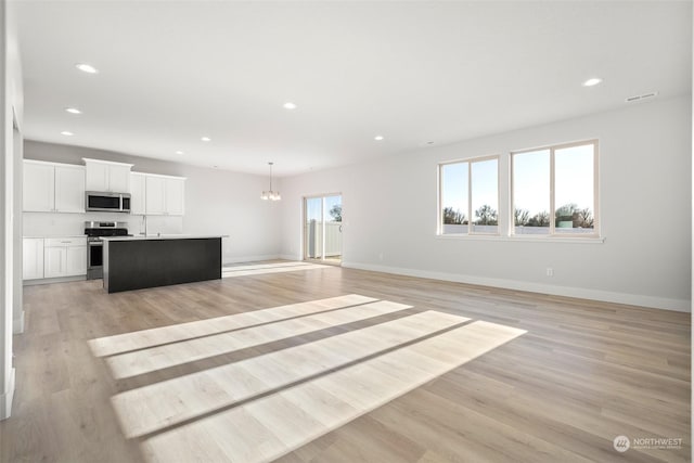 unfurnished living room featuring a chandelier and light hardwood / wood-style flooring