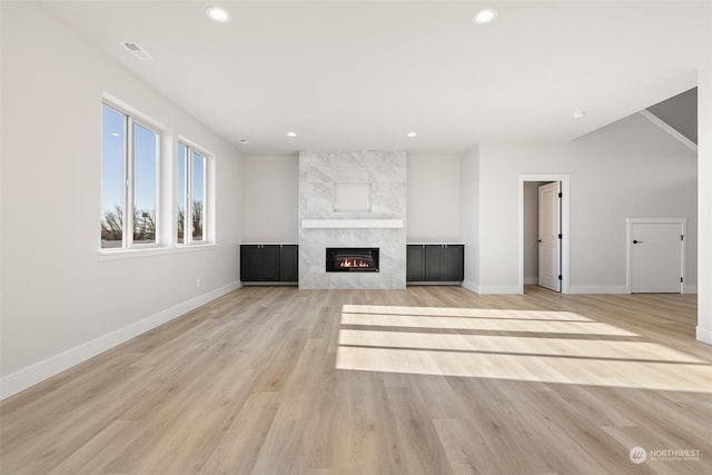 unfurnished living room featuring a tiled fireplace and light hardwood / wood-style floors