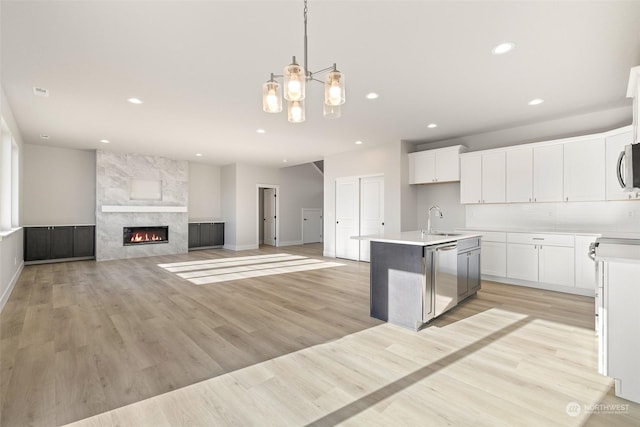 kitchen with sink, white cabinets, hanging light fixtures, stainless steel appliances, and a center island with sink