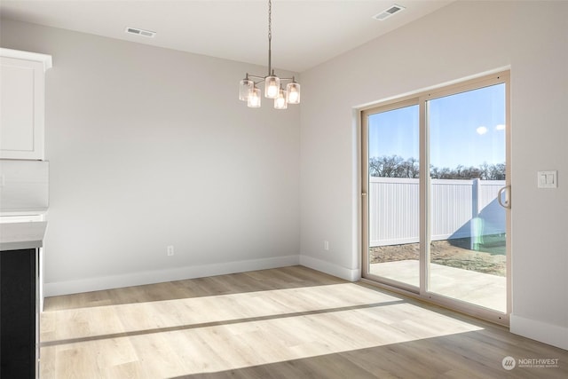 unfurnished dining area featuring a chandelier and light hardwood / wood-style flooring