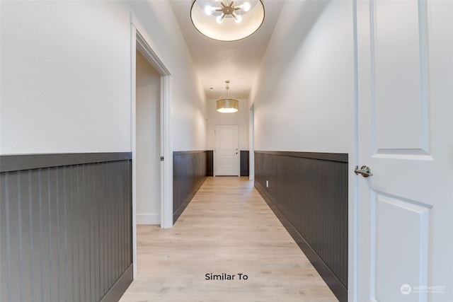 corridor with a notable chandelier and light wood-type flooring