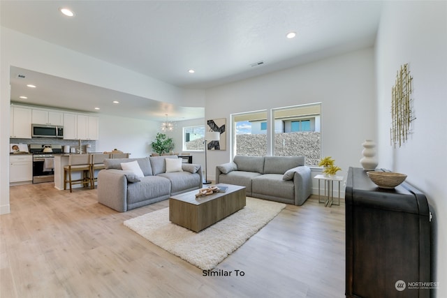 living room with light hardwood / wood-style flooring and an inviting chandelier