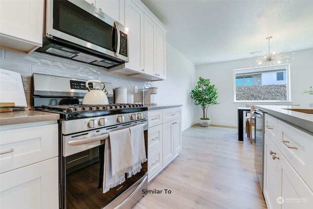 kitchen featuring decorative light fixtures, white cabinets, stainless steel appliances, and light hardwood / wood-style floors