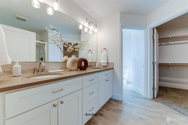 bathroom featuring a shower with door, vanity, toilet, and hardwood / wood-style floors