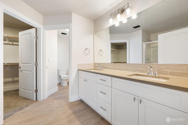 bathroom featuring hardwood / wood-style flooring, vanity, walk in shower, and toilet