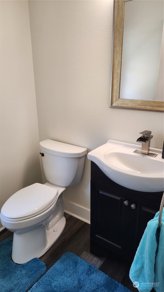 bathroom with wood-type flooring, toilet, and vanity