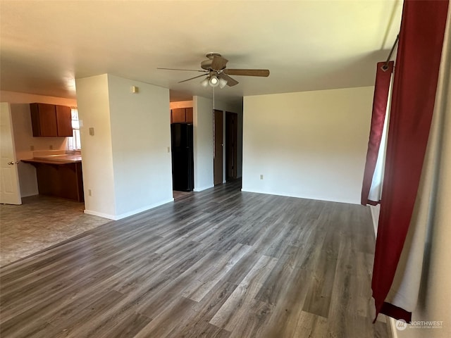 unfurnished living room featuring dark wood-type flooring and ceiling fan