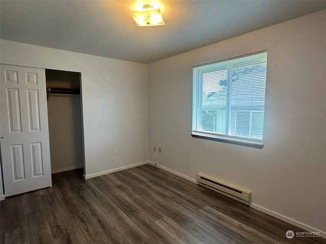 unfurnished bedroom with a baseboard radiator, a closet, and dark hardwood / wood-style flooring