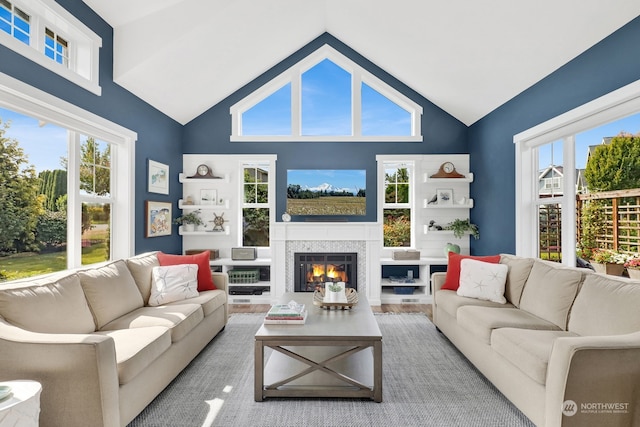 living room featuring a tiled fireplace, high vaulted ceiling, and light hardwood / wood-style floors