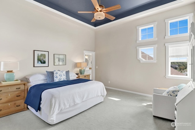 bedroom with light carpet, ornamental molding, a high ceiling, and ceiling fan