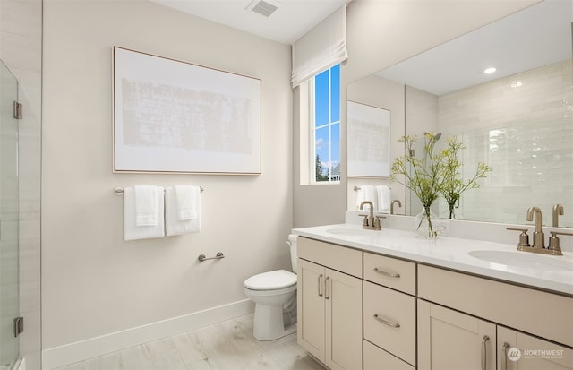 bathroom with wood-type flooring, a shower with door, vanity, and toilet