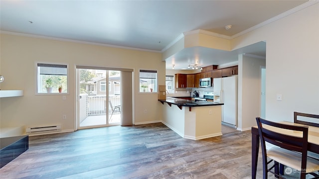 kitchen with hardwood / wood-style flooring, stainless steel appliances, a baseboard radiator, kitchen peninsula, and ornamental molding