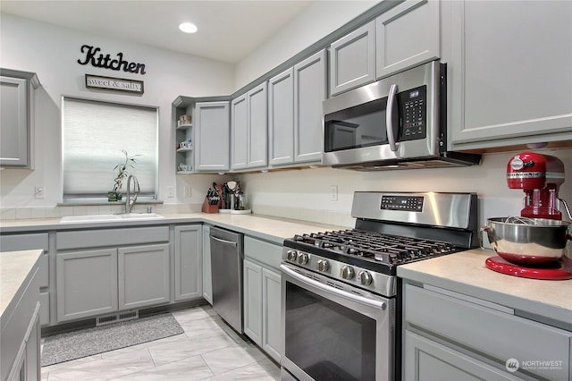 kitchen with gray cabinets, stainless steel appliances, and sink