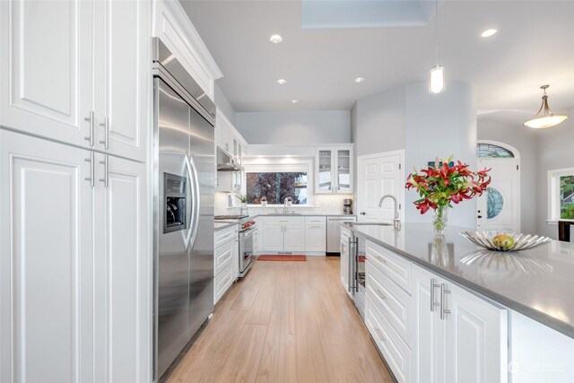 kitchen with light hardwood / wood-style floors, white cabinetry, and premium appliances