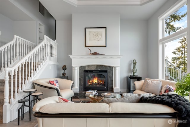 living room with ornamental molding, a premium fireplace, plenty of natural light, and hardwood / wood-style floors