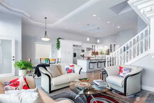 living room with baseboards, a raised ceiling, light wood-style flooring, stairs, and recessed lighting