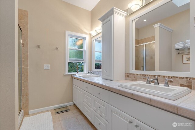 bathroom with tile patterned flooring, vanity, backsplash, and walk in shower