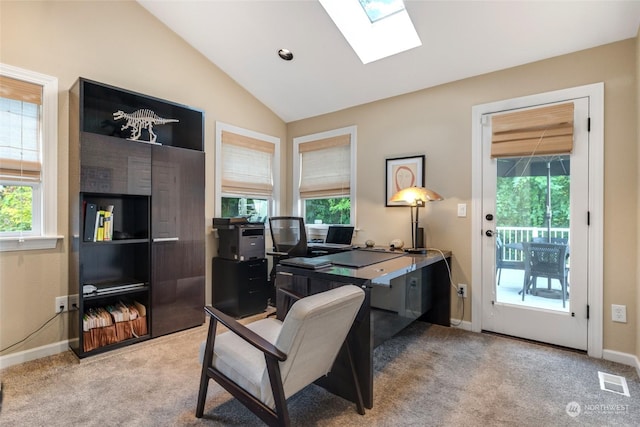 office area featuring lofted ceiling with skylight, carpet, visible vents, and baseboards